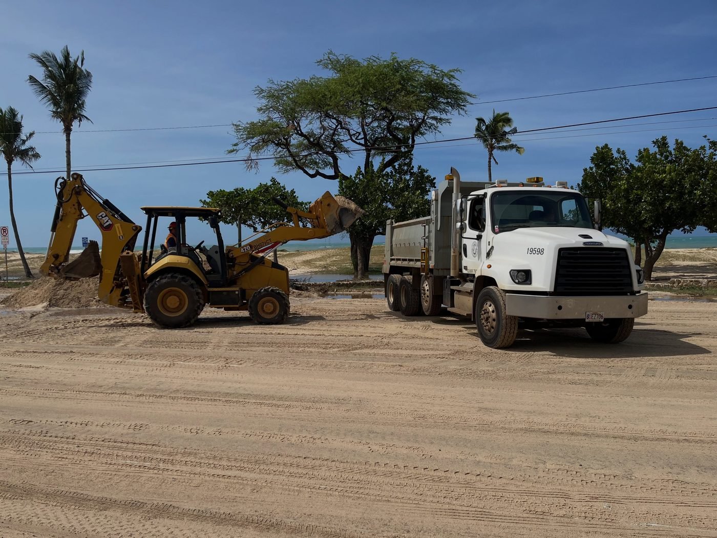 Crews removing sand and debris from Farrington Highway in Mākaha, Oʻahu after Hurricane Lowell